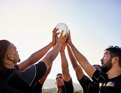 Des joueurs de rugby sautant pour attraper le ballon lors d'une touche, mettant en avant le travail d'équipe, la coordination et les performances athlétiques sur le terrain