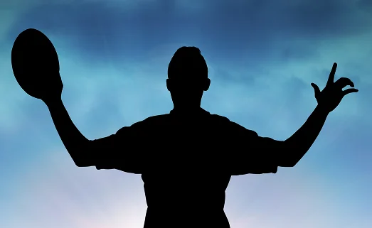 Silhouette d'un joueur de rugby tenant un ballon, les bras levés, sur fond de ciel bleu, symbolisant la force et l'action dans le rugby